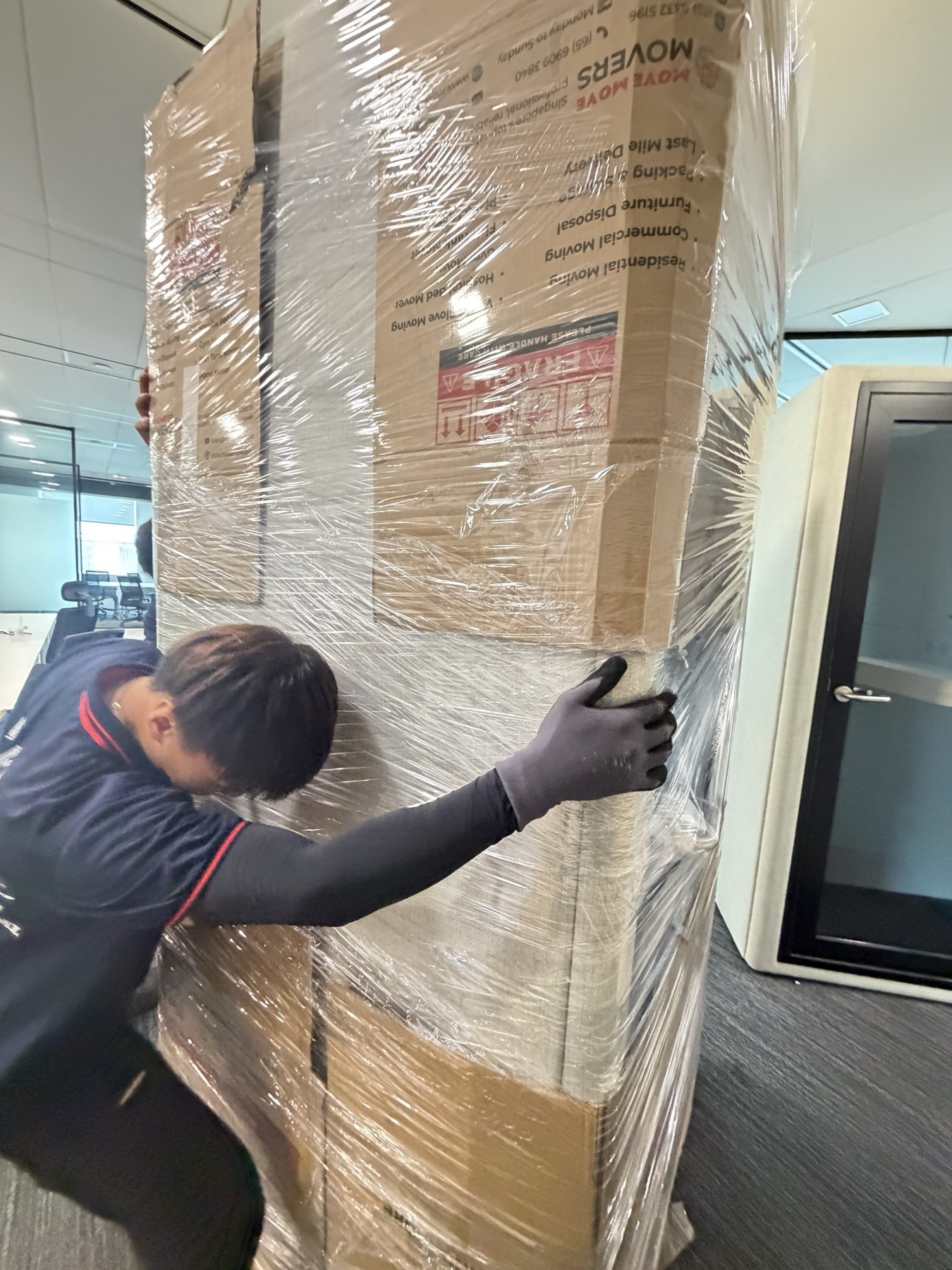 Wrapped commercial equipment moving through an office space with protective handling